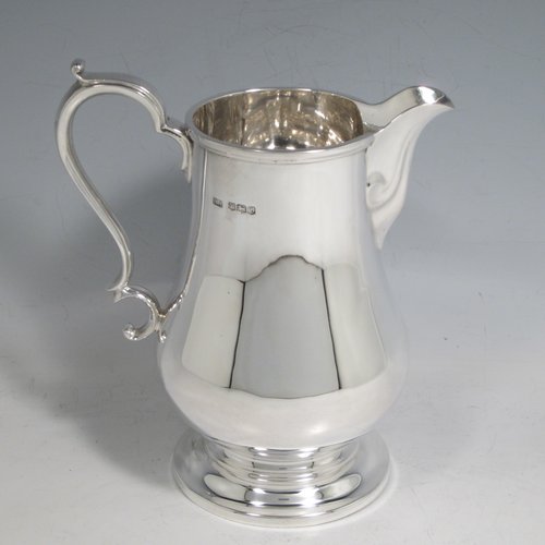 Sterling silver water jug, in a George I beer jug style, having a plain round bellied body, sparrow-beak spout, scroll handle, and sitting on a pedestal foot. Made by Henry Atkins of Sheffield in 1936. The dimensions of this fine hand-made silver water jug are height 21 cms (8.25 inches), length 16.5 cms (6.5 inches), length 14 cms (5.5 inches), and it weighs approx. 449g (14.5 troy ounces). Please note that this silver water jugs size would be perfect for serving two people.