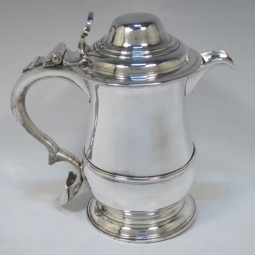 A very handsome Antique Georgian Sterling Silver water or beer jug, having a plain round bellied body with an applied central reeded girdle, a plain pouring spout, a scroll handle with heart-shaped terminal, a hinged domed lid with pierced thumb-piece, and sitting on a plain round stepped pedestal foot. Made by John Payne of London in 1754. The dimensions of this fine hand-made antique silver beer or water jug are height 21 cms (8.5 inches), length 21 cms (8.5 inches), and it weighs approx. 870g (28 troy ounces).  