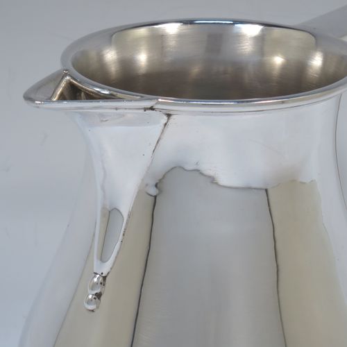 A very handsome and large Sterling Silver water jug, in a George I beer jug style, having a plain round bellied body, sparrow-beak spout, a scroll handle, and sitting on a collet foot. Made by Edward Barnard of London in 1975. The dimensions of this fine hand-made silver water jug are height 18 cms (7 inches), length 19 cms (7.5 inches), capacity of 1.5 litres (2.64 pints) and it weighs approx. 747g (24 troy ounces).