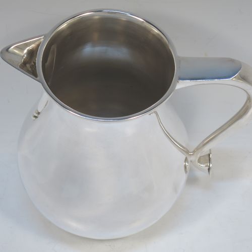 A very handsome and large Sterling Silver water jug, in a George I beer jug style, having a plain round bellied body, sparrow-beak spout, a scroll handle, and sitting on a collet foot. Made by Edward Barnard of London in 1975. The dimensions of this fine hand-made silver water jug are height 18 cms (7 inches), length 19 cms (7.5 inches), capacity of 1.5 litres (2.64 pints) and it weighs approx. 747g (24 troy ounces).