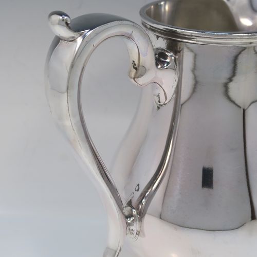 A very handsome and large Silver Plated water jug, in a George I beer jug style, having a plain round bellied body, a sparrow-beak spout, a scroll handle, and sitting on a pedestal foot. This elegant silver-plated water or beer jug was made in ca. 1930. The dimensions of this fine hand-made silver plated water jug are height 23 cms (9 inches), and length 22 cms (8.5 inches).   