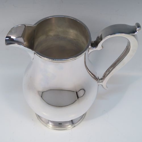 A very handsome and large Silver Plated water jug, in a George I beer jug style, having a plain round bellied body, a sparrow-beak spout, a scroll handle, and sitting on a pedestal foot. This elegant silver-plated water or beer jug was made in ca. 1930. The dimensions of this fine hand-made silver plated water jug are height 23 cms (9 inches), and length 22 cms (8.5 inches).   
