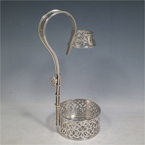 An Antique Victorian Silver Plated wine bottle cradle or holder, having a round straight-sided base with hand-pierced floral decoration, a sliding scroll handle with matching neck and floral retaining screw. Made by Elkington & Co., of Sheffield in ca. 1880. The dimensions of this fine hand-made antique silver-plated wine bottle holder or cradle are height 28 cms (11 inches), and diameter of base 10 cms (4 inches). Please note that this wine bottle cradle or holder will accept a 75cl bottle, (bottle shown for display purposes only).
