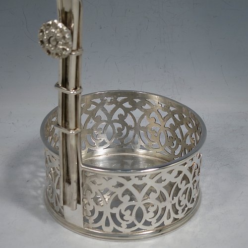 An Antique Victorian Silver Plated wine bottle cradle or holder, having a round straight-sided base with hand-pierced floral decoration, a sliding scroll handle with matching neck and floral retaining screw. Made by Elkington & Co., of Sheffield in ca. 1880. The dimensions of this fine hand-made antique silver-plated wine bottle holder or cradle are height 28 cms (11 inches), and diameter of base 10 cms (4 inches). Please note that this wine bottle cradle or holder will accept a 75cl bottle, (bottle shown for display purposes only).
