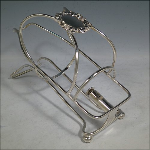 An Antique Victorian Silver Plated wine bottle cradle or holder, having a wire-work body with a cast wine-label style cartouche attached to the handle, and sitting on a base with two cushion feet. Made in Sheffield in ca. 1880. The dimensions of this fine hand-made antique silver wine bottle holder or cradle are length 24 cms (9.5 inches), width 10 cms (4 inches), and height 16.5 cms (6.5 inches). Please note that this wine bottle cradle will accept a standard 75cl, (bottle shown for display purposes only).    