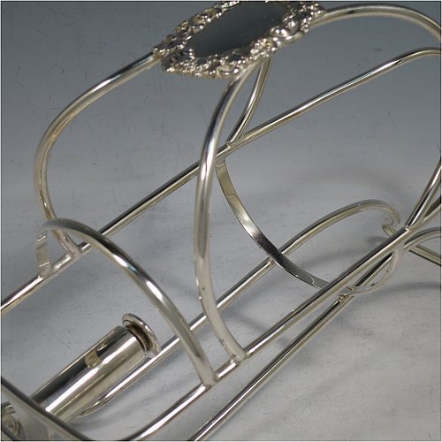 An Antique Victorian Silver Plated wine bottle cradle or holder, having a wire-work body with a cast wine-label style cartouche attached to the handle, and sitting on a base with two cushion feet. Made in Sheffield in ca. 1880. The dimensions of this fine hand-made antique silver wine bottle holder or cradle are length 24 cms (9.5 inches), width 10 cms (4 inches), and height 16.5 cms (6.5 inches). Please note that this wine bottle cradle will accept a standard 75cl, (bottle shown for display purposes only).    