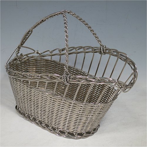 An Antique Victorian Silver Plated wine bottle cradle or holder, having an oval straight-sided body with tapering sides, with an attached carrying handle, and sitting on a flat base, all made in a basket-weave style with individual wire-work decoration. Made in Sheffield in ca. 1900. The dimensions of this fine hand-made antique silver wine bottle holder or cradle are length 23 cms (9 inches), width 12 cms (4.75 inches), and height 18 cms (7 inches). Please note that this wine bottle cradle will accept a standard 75cl, (bottle shown for display purposes only).    