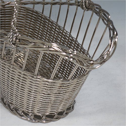 An Antique Victorian Silver Plated wine bottle cradle or holder, having an oval straight-sided body with tapering sides, with an attached carrying handle, and sitting on a flat base, all made in a basket-weave style with individual wire-work decoration. Made in Sheffield in ca. 1900. The dimensions of this fine hand-made antique silver wine bottle holder or cradle are length 23 cms (9 inches), width 12 cms (4.75 inches), and height 18 cms (7 inches). Please note that this wine bottle cradle will accept a standard 75cl, (bottle shown for display purposes only).