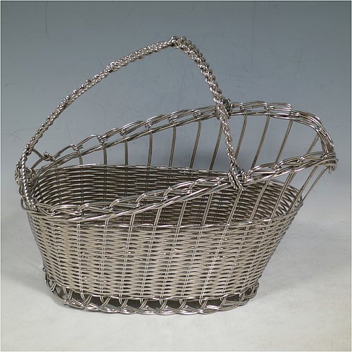 An Antique Victorian Silver Plated wine bottle cradle or holder, having an oval straight-sided body with tapering sides, with an attached carrying handle, and sitting on a flat base, all made in a basket-weave style with individual wire-work decoration. Made in Sheffield in ca. 1900. The dimensions of this fine hand-made antique silver wine bottle holder or cradle are length 23 cms (9 inches), width 12 cms (4.75 inches), and height 18 cms (7 inches). Please note that this wine bottle cradle will accept a standard 75cl, (bottle shown for display purposes only).