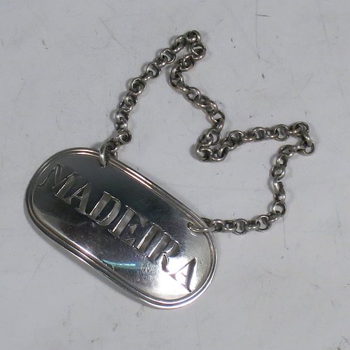 A rare 18th century Antique Georgian Sterling Silver wine decanter label, having a plain elongated oval shaped body, with a reeded border, hand-pierced for Madeira, and with its original bottle chain. Made by Thomas Phipps & Edward Robinson of London 1795. The dimensions of this fine hand-made antique silver decanter wine label are height 2.5 cms (1 inch), length 4.5 cms (1.75 inches), and it weighs approx. 10g (0.32 troy ounces).