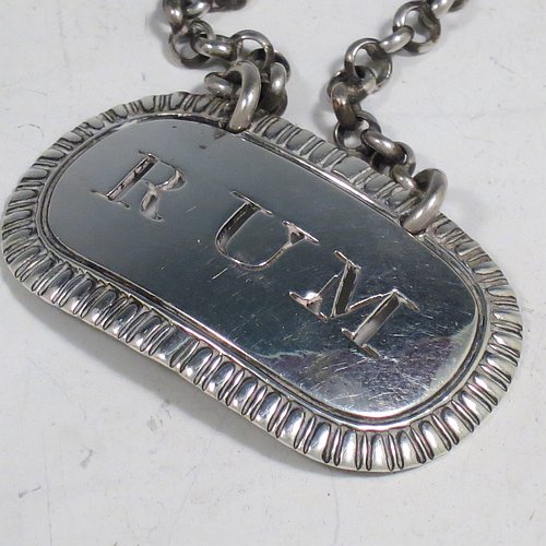 A rare set of three Antique Georgian Sterling Silver wine decanter labels, having plain elongated oval shaped bodies, with hand-chased gadroon borders, all hand-pierced for Gin, Rum, and Brandy, and with their original bottle chains. Made by John Reily of London in 1817. The dimensions of these fine hand-made antique silver decanter wine labels are height 2.5 cms (1 inch), length 4.5 cms (1.75 inches), and they weigh a total of approx. 44g (1.4 troy ounces).