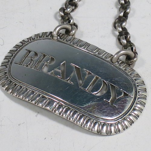 A rare set of three Antique Georgian Sterling Silver wine decanter labels, having plain elongated oval shaped bodies, with hand-chased gadroon borders, all hand-pierced for Gin, Rum, and Brandy, and with their original bottle chains. Made by John Reily of London in 1817. The dimensions of these fine hand-made antique silver decanter wine labels are height 2.5 cms (1 inch), length 4.5 cms (1.75 inches), and they weigh a total of approx. 44g (1.4 troy ounces).