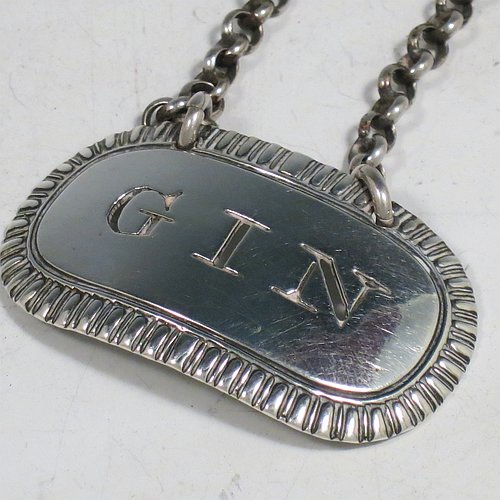 A rare set of three Antique Georgian Sterling Silver wine decanter labels, having plain elongated oval shaped bodies, with hand-chased gadroon borders, all hand-pierced for Gin, Rum, and Brandy, and with their original bottle chains. Made by John Reily of London in 1817. The dimensions of these fine hand-made antique silver decanter wine labels are height 2.5 cms (1 inch), length 4.5 cms (1.75 inches), and they weigh a total of approx. 44g (1.4 troy ounces).