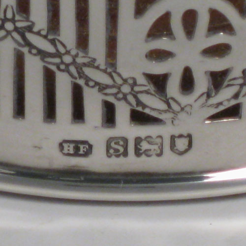 Sterling silver pair of wine bottle table coasters, having round bodies with hand-pierced decoration and engraved swags, with wood-turned bases and silver buttons, and applied beaded borders. Made by Henry Freeman Ltd., of London in 1913. The dimensions of these wine coasters are diameter 13 cms (5 inches), height 4 cms (1.5 inches).