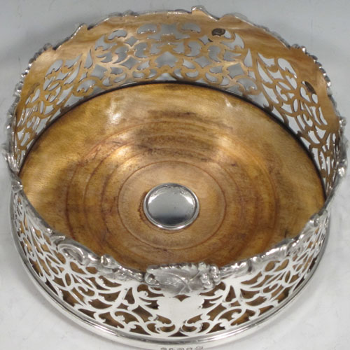 Antique Victorian silver plated pair of large wine bottle coasters, having straight sides with hand-pierced floral decoration, applied cast grape-vine borders, and wood-turned bases with silver buttons. Made by Martin Hall & Co., in ca. 1860. The dimensions of these fine hand-made silver-plated wine coasters are diameter 14 cms (5.5 inches), and height 7 cms (2.75 inches).