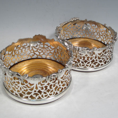 Antique Victorian silver plated pair of large wine bottle coasters, having straight sides with hand-pierced floral decoration, applied cast grape-vine borders, and wood-turned bases with silver buttons. Made by Martin Hall & Co., in ca. 1860. The dimensions of these fine hand-made silver-plated wine coasters are diameter 14 cms (5.5 inches), and height 7 cms (2.75 inches).