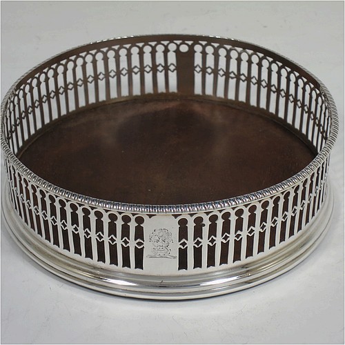 A very pretty Antique Georgian Sterling Silver pair of Neoclassical style wine coasters, having hand-pierced walls, applied gadroon borders, and plain oak bases. Made by Philip Freeman of London in 1775. The dimensions of this fine hand-made antique pair of silver wine bottle coasters are diameter 12 cms (4.75 inches), and height 3.5 cms (1.3 inches).   