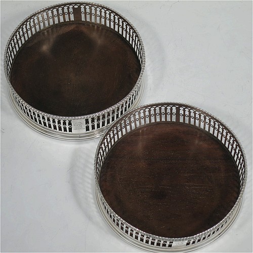 A very pretty Antique Georgian Sterling Silver pair of Neoclassical style wine coasters, having hand-pierced walls, applied gadroon borders, and plain oak bases. Made by Philip Freeman of London in 1775. The dimensions of this fine hand-made antique pair of silver wine bottle coasters are diameter 12 cms (4.75 inches), and height 3.5 cms (1.3 inches).   