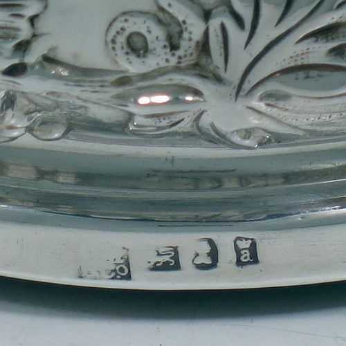 An Antique Georgian Sterling Silver pair of table wine bottle coasters, having round bellied bodies with hand-chased grape and vine decoration, and applied shell and scroll borders, and wood turned bases with silver buttons. Made S. C. Younge & Co of Sheffield in 1824. The dimensions of this fine pair of hand-made antique silver wine bottle coasters are diameter 16.5 cms (6.5 inches), and height 5 cms (2 inches).    
