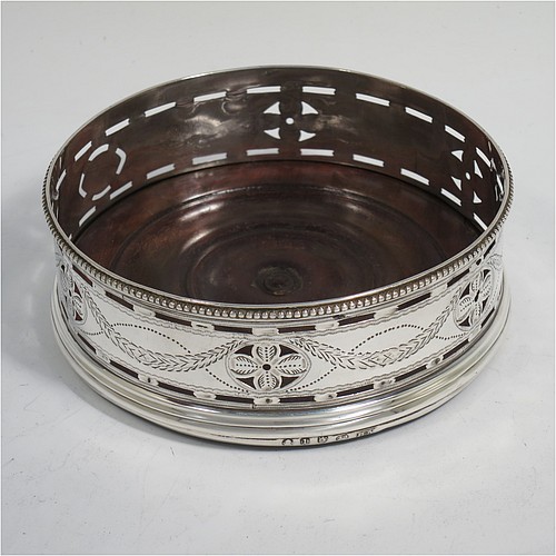 A very pretty Antique Georgian Sterling Silver pair of Neoclassical style wine coasters, having hand-pierced walls with hand-engraved neoclassical decoration, applied bead-edge borders, and oak hand-turned bases. Made by Benjamin Mountigue of London in 1786. The dimensions of this fine hand-made antique pair of neoclassical style silver wine bottle coasters are diameter 11.5 cms (4.5 inches), and height 4 cms (1.5 inches).