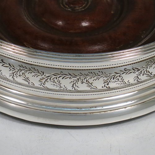 An Antique Georgian Sterling Silver very handsome and heavy set of four table wine bottle coasters, having round bellied bodies, with applied reed-edged borders and bands of hand-engraved floral decoration, and with wood-turned bases. Made by John Emes of London in 1800. The dimensions of these fine hand-made antique silver wine bottle coasters are diameter 13 cms (5 inches), and height 4 cms (1.5 inches). Please note that one of the coaster woods has been replaced at a later date and is of a slightly different colour.   