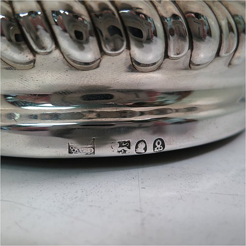 An Antique Georgian Sterling Silver pair of table wine bottle coasters, in a Regency style having round bodies with a band of hand-chased fluted decoration, applied gadroon, scroll, & shell borders, and wood turned bases with silver buttons. Made S. C. Younge & Co of Sheffield in 1815. The dimensions of this fine pair of hand-made antique silver wine bottle coasters are diameter 16 cms (6.3 inches), and height 4 cms (1.5 inches).
