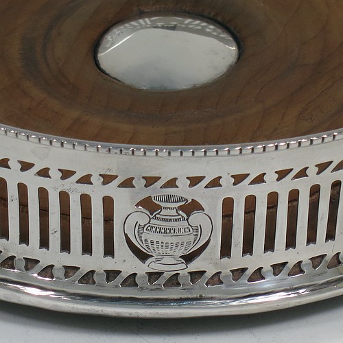 A very pretty Antique Neoclassical style Sterling Silver wine bottle table coaster, having a round hand-pierced body, with an applied bead-edged border, and a wood-turned base with silver button. Made by Harry Freeman of London in 1915. The dimensions of this fine hand-made antique silver wine bottle coaster are diameter 14.5 cms (5.75 inches), and height 4 cms (1.5 inches).