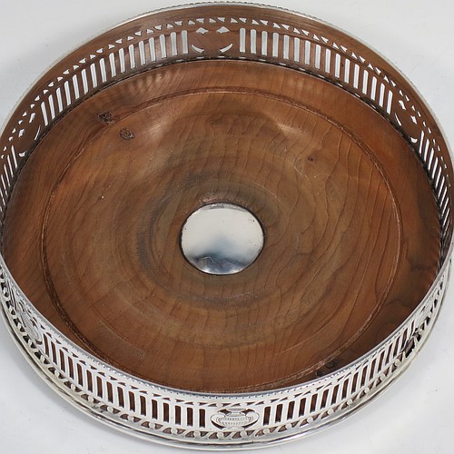 A very pretty Antique Neoclassical style Sterling Silver wine bottle table coaster, having a round hand-pierced body, with an applied bead-edged border, and a wood-turned base with silver button. Made by Harry Freeman of London in 1915. The dimensions of this fine hand-made antique silver wine bottle coaster are diameter 14.5 cms (5.75 inches), and height 4 cms (1.5 inches).