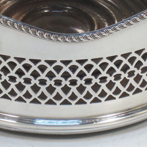 A very pretty Neoclassical style Sterling Silver wine bottle table coaster, having a round hand-pierced body, with an applied gadroon border, and a wood-turned base. Made by S. J. Rose of Birmingham in 1973. The dimensions of this fine hand-made silver wine bottle coaster are diameter 13.5 cms (5.3 inches), and height 5.5 cms (2.25 inches).