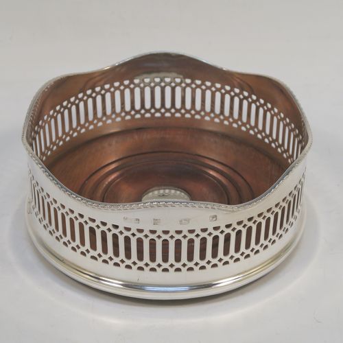 A large and very elegant Sterling Silver pair of Neoclassical style wine coasters, having hand-pierced walls with applied wavy gadroon-edged borders, and plain oak-turned bases with silver buttons. These beautiful silver bottle coasters were made by R. E. Porter of Birmingham in 1989. The dimensions of this fine hand-made pair of silver wine bottle coasters are diameter 14 cms (5.5 inches), and height 5.5 cms (2.25 inches).