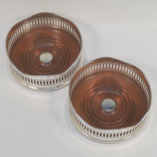 A large and very elegant Sterling Silver pair of Neoclassical style wine coasters, having hand-pierced walls with applied wavy gadroon-edged borders, and plain oak-turned bases with silver buttons. These beautiful silver bottle coasters were made by R. E. Porter of Birmingham in 1989. The dimensions of this fine hand-made pair of silver wine bottle coasters are diameter 14 cms (5.5 inches), and height 5.5 cms (2.25 inches).