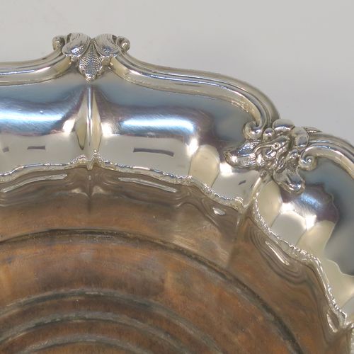 A very handsome Antique Georgian Old Sheffield plated pair of table wine coasters, having round bodies with melon fluted sides, applied floral and scroll borders, and wood-turned bases with silver buttons. These elegant antique wine bottle coasters were made in ca. 1830. The dimensions of this fine hand-made pair of antique Old Sheffield silver plated wine coasters are diameter 18 cms (7 inches), and height 5 cms (2 inches).