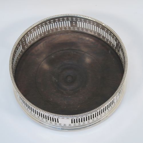A very handsome Antique Georgian Old Sheffield Plated pair of Neoclassical style wine coasters, having hand-pierced walls, applied bead-edged borders, and plain oak-turned bases. These beautiful antique silver-plated bottle coasters were made in ca. 1780. The dimensions of this fine hand-made antique pair of Old Sheffield Plated silver wine bottle coasters are diameter 13 cms (5.25 inches), and height 4.5 cms (1.75 inches).