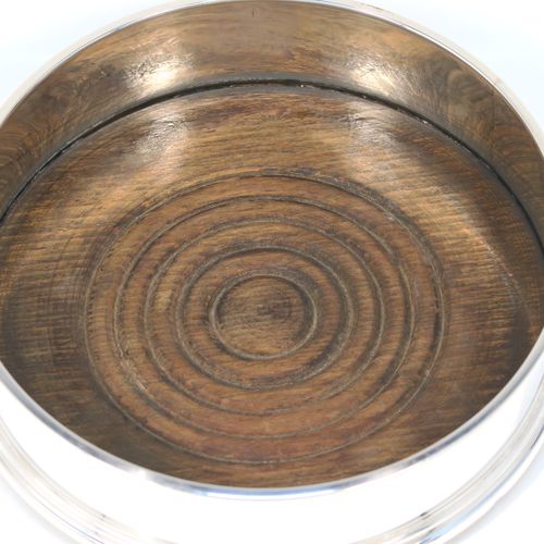A very elegant pair of Sterling Silver table wine bottle coasters, having plain round straight sided bodies, with applied reeded top borders, and stained fruit wood turned bases. This handsome pair of silver wine bottle coasters were made by Richard Knight of London in 1970. The dimensions of these fine hand-made silver wine coasters are diameter 12.5 cms (5 inches), and height 4 cms (1.5 inches).