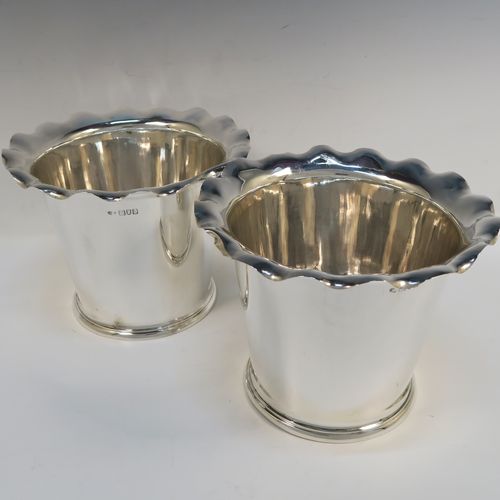 A very elegant pair of Antique Edwardian Sterling Silver wine bottle coolers, having plain round bodies with tapering sides and wavey-edged top borders, and sitting on collet feet. These elegant antique silver wine bottle coolers were made by Goldsmiths and Silversmiths of London in 1903. The dimensions of this fine pair of hand-made antique silver wine coolers are height 15 cms (6 inches), diameter at top 20 cms (8 inches), and they weigh a total of 1,210g (39 toy ounces).   