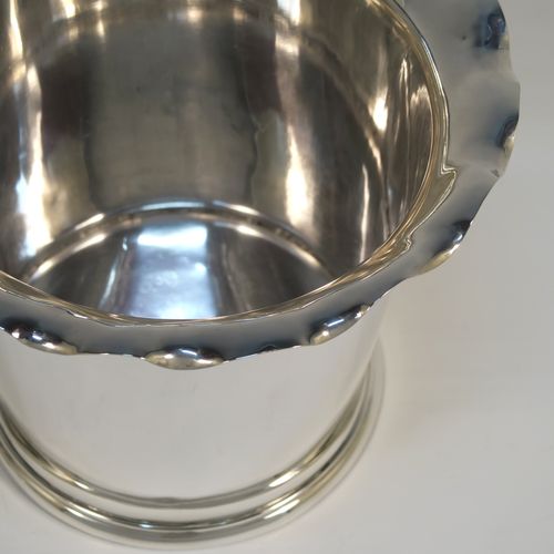 A very elegant pair of Antique Edwardian Sterling Silver wine bottle coolers, having plain round bodies with tapering sides and wavey-edged top borders, and sitting on collet feet. These elegant antique silver wine bottle coolers were made by Goldsmiths and Silversmiths of London in 1903. The dimensions of this fine pair of hand-made antique silver wine coolers are height 15 cms (6 inches), diameter at top 20 cms (8 inches), and they weigh a total of 1,210g (39 toy ounces).