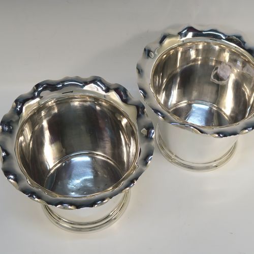 A very elegant pair of Antique Edwardian Sterling Silver wine bottle coolers, having plain round bodies with tapering sides and wavey-edged top borders, and sitting on collet feet. These elegant antique silver wine bottle coolers were made by Goldsmiths and Silversmiths of London in 1903. The dimensions of this fine pair of hand-made antique silver wine coolers are height 15 cms (6 inches), diameter at top 20 cms (8 inches), and they weigh a total of 1,210g (39 toy ounces).