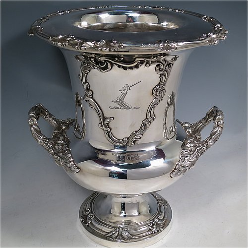An Antique Georgian Old Sheffield plated wine cooler, in the Campagna style, with cast floral borders, a pair of cast anthemion leaf handles, and applied scroll cartouches either side. All with original interior and cover. Made in ca. 1835. The dimensions of this fine hand-made antique Old Sheffield plated wine cooler are height 30.5 cms (12 inches), width across handles 26 cms (10.25inches). Please note that this item is crested on one side.   