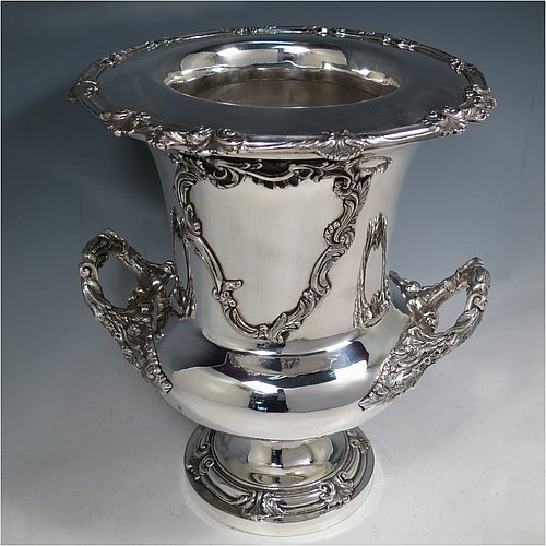 An Antique Georgian Old Sheffield plated wine cooler, in the Campagna style, with cast floral borders, a pair of cast anthemion leaf handles, and applied scroll cartouches either side. All with original interior and cover. Made in ca. 1835. The dimensions of this fine hand-made antique Old Sheffield plated wine cooler are height 30.5 cms (12 inches), width across handles 26 cms (10.25inches). Please note that this item is crested on one side.