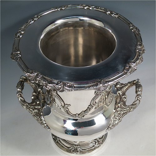 An Antique Georgian Old Sheffield plated wine cooler, in the Campagna style, with cast floral borders, a pair of cast anthemion leaf handles, and applied scroll cartouches either side. All with original interior and cover. Made in ca. 1835. The dimensions of this fine hand-made antique Old Sheffield plated wine cooler are height 30.5 cms (12 inches), width across handles 26 cms (10.25inches). Please note that this item is crested on one side.
