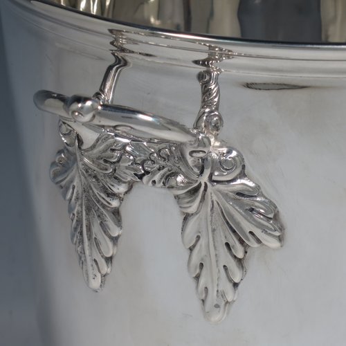 A Sterling Silver wine bottle cooler / trophy cup, having a plain round baluster body, with two cast handles with grape-vine decoration, and sitting on a collet foot. Made by Roberts & Belk of Sheffield in 1982. The dimensions of this fine hand-made silver wine cooler are height 19 cms (7.5 inches), and it weighs approx. 1,193g (38.5 troy ounces)