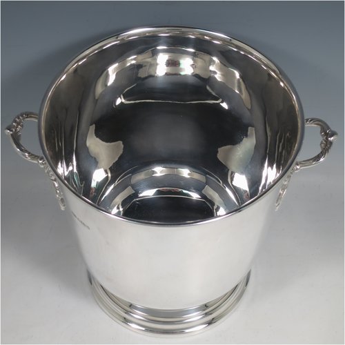 A Sterling Silver wine bottle cooler / trophy cup, having a plain round baluster body, with two cast handles with grape-vine decoration, and sitting on a collet foot. Made by Roberts & Belk of Sheffield in 1982. The dimensions of this fine hand-made silver wine cooler are height 19 cms (7.5 inches), and it weighs approx. 1,193g (38.5 troy ounces)