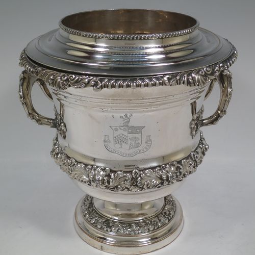 A very handsome Antique Georgian Old Sheffield plated wine cooler, in the Campagna style, with cast gadroon, scroll, and floral borders, a pair of cast side-handles, with original interior and cover, and all sitting on a pedestal foot. Made in ca. 1825. The dimensions of this fine hand-made antique Old Sheffield wine cooler are height 24.5 cms (9.75 inches), width across handles 21 cms (8.25 inches). Please note that this item is crested.   