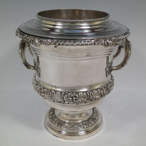 A very handsome Antique Georgian Old Sheffield plated wine cooler, in the Campagna style, with cast gadroon, scroll, and floral borders, a pair of cast side-handles, with original interior and cover, and all sitting on a pedestal foot. Made in ca. 1825. The dimensions of this fine hand-made antique Old Sheffield wine cooler are height 24.5 cms (9.75 inches), width across handles 21 cms (8.25 inches). Please note that this item is crested.