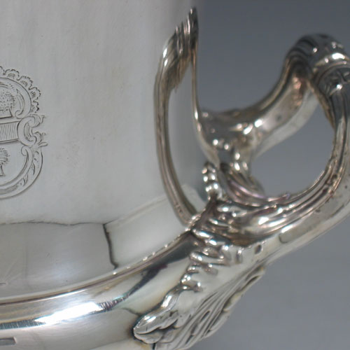 A very hansome pair of Antique Georgian Old Sheffield silver-plated wine coolers in the Campana style, with applied garoon borders, two side-handles with anthemion leaf mounts, with original interiors and covers, and all sitting on pedestal feet. Made in ca. 1815. The dimensions of this fine pair of hand-made antique Old Sheffield silver plated wine coolers are height 27 cms (10.5 inches), width across handles 24 cms (9.5 inches). Please note that these items are crested.