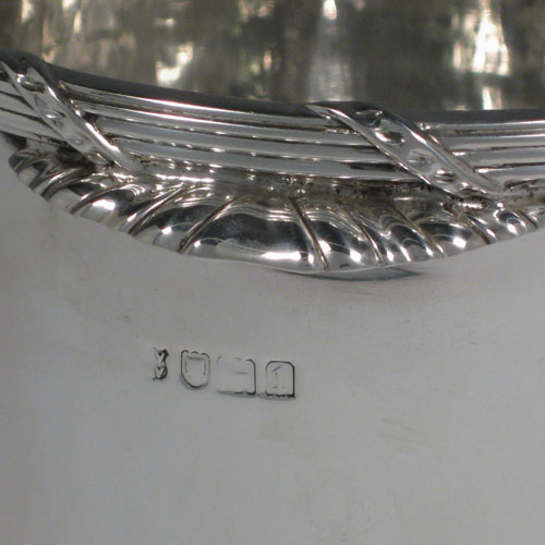 Antique Edwardian sterling silver wine cooler, having a plain cylindrical body, a ribbon and reed top border, two cast fluted handles, and a removable pierced drainer. Made by C.J. Vanders of London in 1906 (originally retailed by Tessiers). Height 16.5 cms (6.5 inches), diameter at top 16.5 cms (6.5 inches). Total weight approx. 1,200g (38.7 troy ounces).