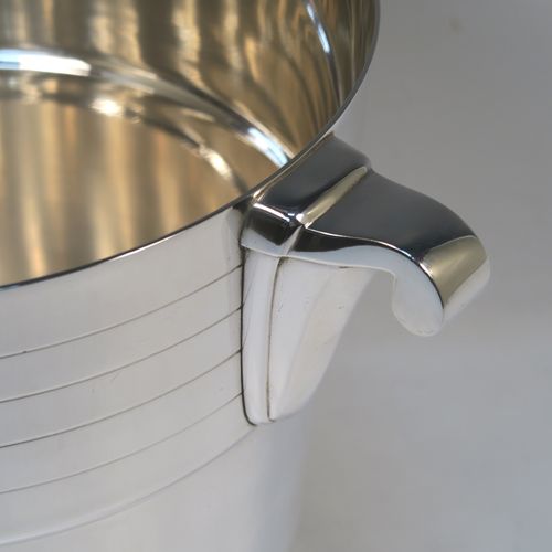 A very elegant Art Deco style Silver Plated wine bottle cooler, having a plain round body with tapering sides, with two bands of hand-engraved reeded decoration, and two cast side-handles, all sitting on a flat base. This beautiful Art Deco silver-plated wine cooler was made in ca. 1930. The dimensions of this fine hand-made silver-plated Art Deco wine cooler are height 20 cms (8 inches), and diameter at lip 19 cms (7.5 inches). Please note that this will easily hold a magnum size bottle.