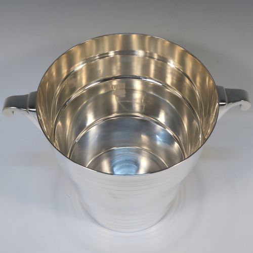 A very elegant Art Deco style Silver Plated wine bottle cooler, having a plain round body with tapering sides, with two bands of hand-engraved reeded decoration, and two cast side-handles, all sitting on a flat base. This beautiful Art Deco silver-plated wine cooler was made in ca. 1930. The dimensions of this fine hand-made silver-plated Art Deco wine cooler are height 20 cms (8 inches), and diameter at lip 19 cms (7.5 inches). Please note that this will easily hold a magnum size bottle.