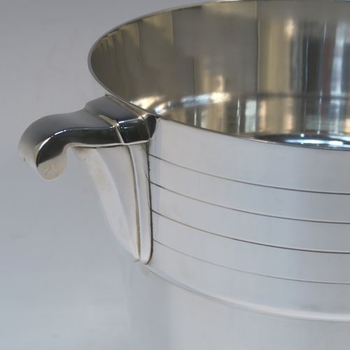 A very elegant Art Deco style Silver Plated wine bottle cooler, having a plain round body with tapering sides, with two bands of hand-engraved reeded decoration, and two cast side-handles, all sitting on a flat base. This beautiful Art Deco silver-plated wine cooler was made in ca. 1930. The dimensions of this fine hand-made silver-plated Art Deco wine cooler are height 20 cms (8 inches), and diameter at lip 19 cms (7.5 inches). Please note that this will easily hold a magnum size bottle.
