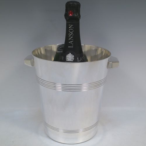A very handsome Art Deco style Silver Plated wine bottle cooler, having a plain round body with tapering sides, with two cast angular side-handles, and two bands of hand-chased reeded decoration, all sitting on a flat base. Made in ca. 1930. The dimensions of this fine hand-made silver-plated wine cooler are height 21 cms (8.25 inches), and diameter at lip 18.5 cms (7.25 inches). Please note that this will easily hold a magnum size bottle.